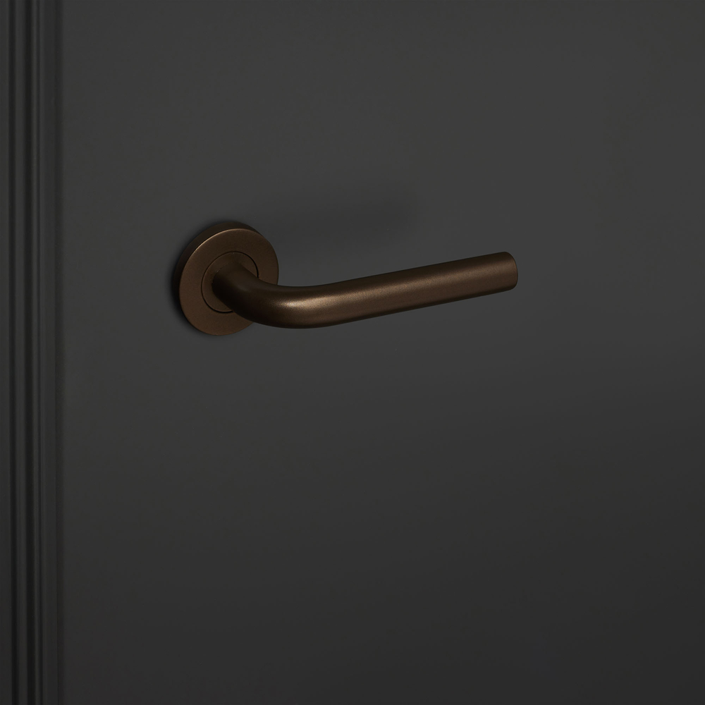 Oristano_brons_rond_rozet_zwarte_deur